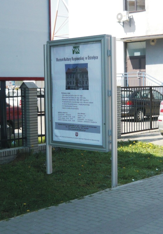 Duża, srebrna, magnetyczna gablota zewnętrzna, dwustronna, wolnostojąca, zamykana na klucz, przeznaczona do wyświetlania ogłoszeń i plakatów w przestrzeni publicznej.