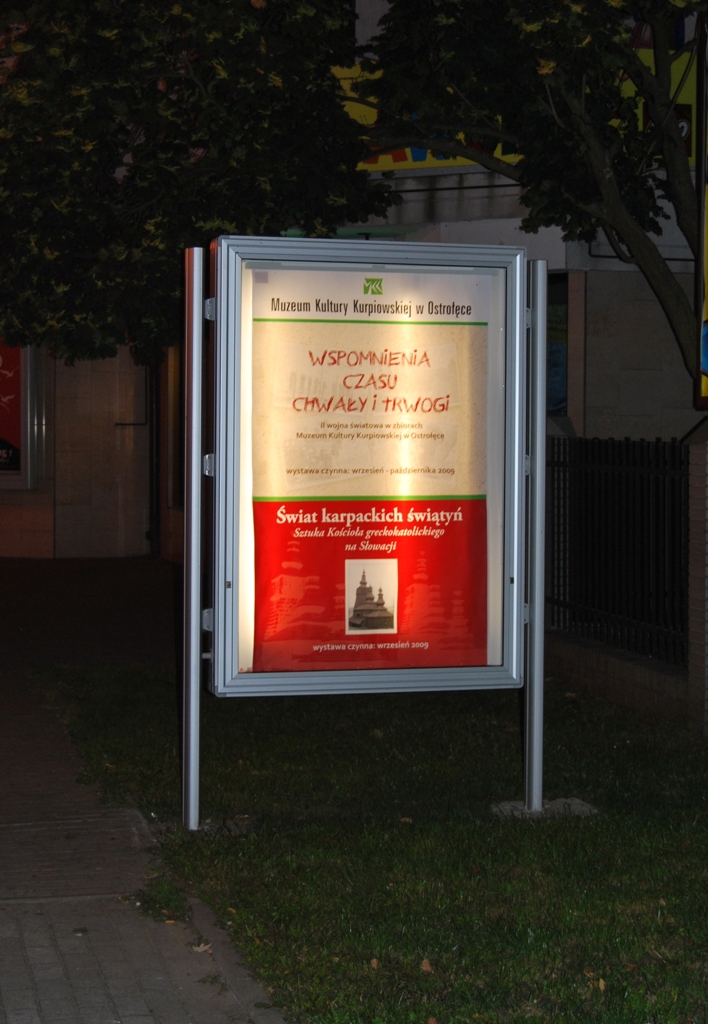 Solidna gablota z ramą z anodowanego aluminium, odporna na warunki atmosferyczne, z magnetycznym panelem tylnym i szybą ze szkła hartowanego lub akrylowego, z nowoczesnym profilem i stalowymi słupkami do wkopania, przeznaczona do użytku zewnętrznego.