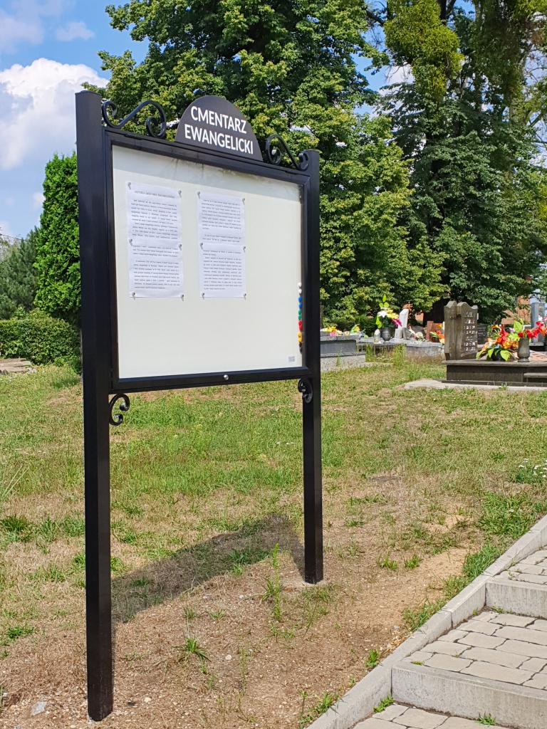 Czarna, wolnostojąca gablota sołecka z nazwą miejscowości, magnetyczna, z zamkiem na klucz, przeznaczona do użytku zewnętrznego, idealna do prezentacji ogłoszeń w przestrzeni publicznej.