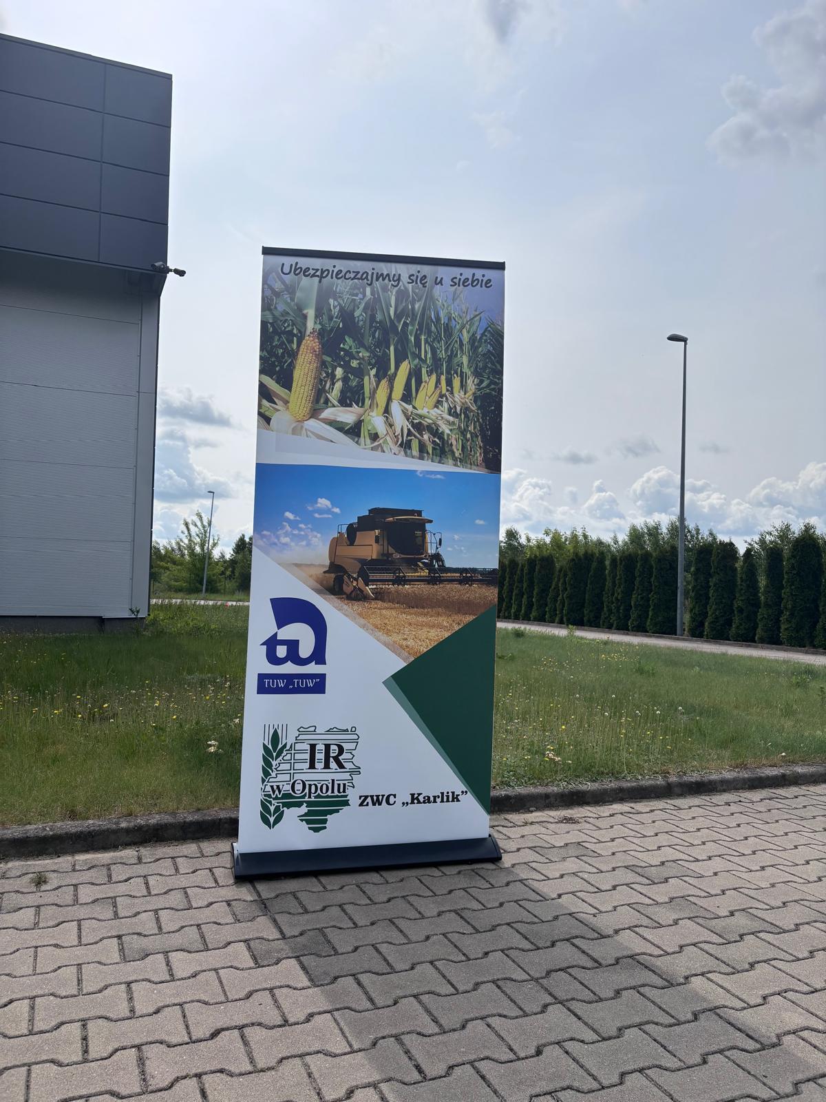 Roll-up z grafiką rolniczą ustawiony na zewnątrz budynku jako nośnik promocyjny.